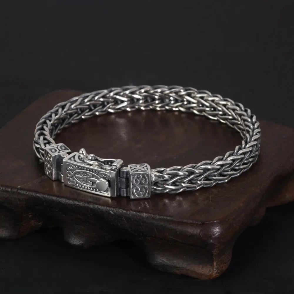 Silver braided bracelet with a clasp on a dark surface
