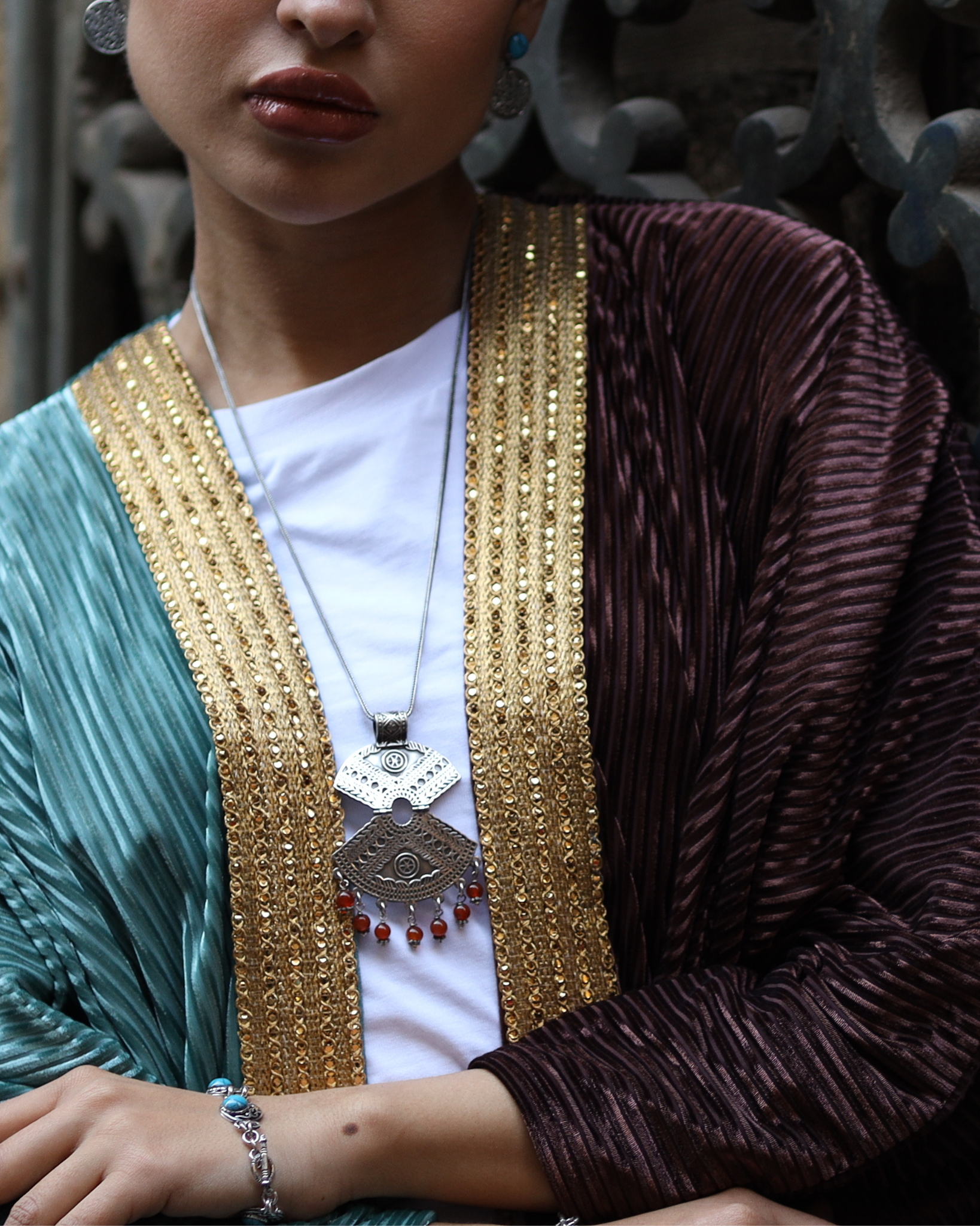 Person wearing a traditional outfit with gold embroidery and a decorative necklace.